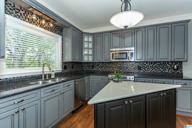 kitchen with sink, appliances with stainless steel finishes, ornamental molding, hanging light fixtures, and a center island