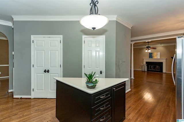 kitchen with stainless steel fridge, crown molding, dark hardwood / wood-style floors, pendant lighting, and a center island