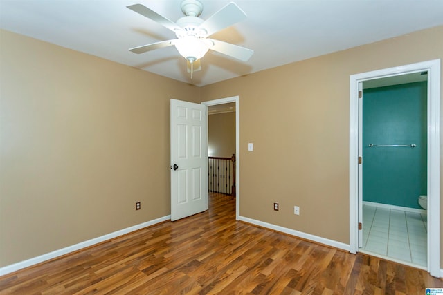 unfurnished bedroom with ensuite bathroom, wood-type flooring, and ceiling fan