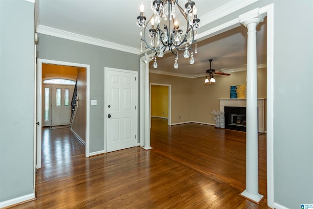 unfurnished dining area featuring ornamental molding, ceiling fan with notable chandelier, dark hardwood / wood-style floors, and decorative columns