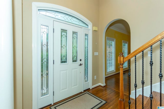 foyer with dark wood-type flooring and crown molding