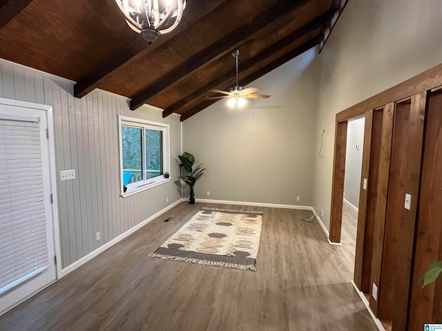 interior space featuring ceiling fan with notable chandelier, wood-type flooring, lofted ceiling with beams, and wood walls