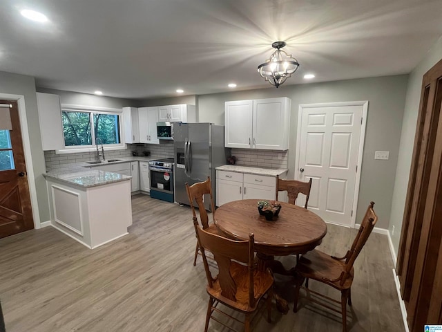 dining room with light wood-type flooring, a notable chandelier, and sink