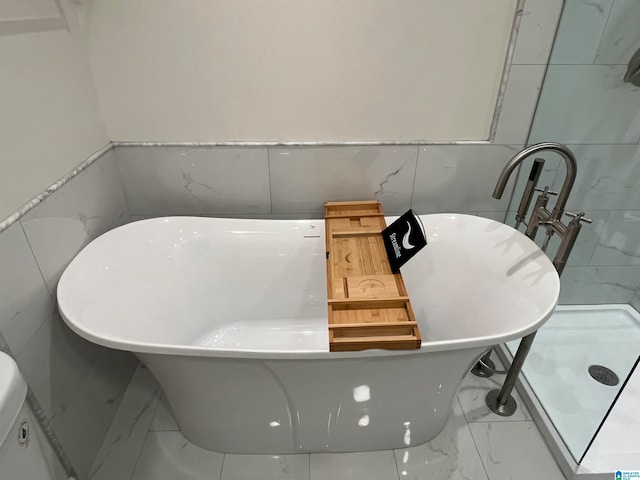 bathroom with a washtub and tile walls