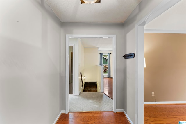 hallway with hardwood / wood-style floors, ornamental molding, and a textured ceiling