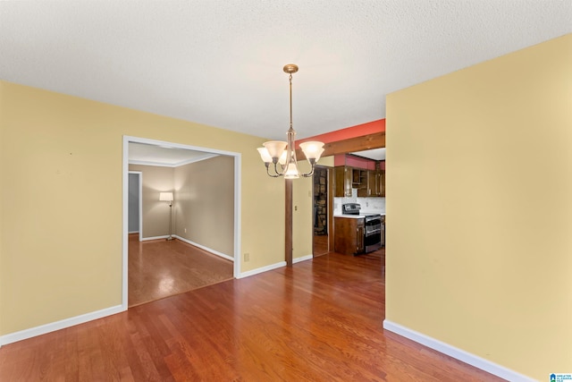 unfurnished dining area featuring dark hardwood / wood-style flooring, a textured ceiling, and a notable chandelier