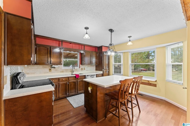 kitchen with a center island, sink, wood-type flooring, decorative light fixtures, and decorative backsplash