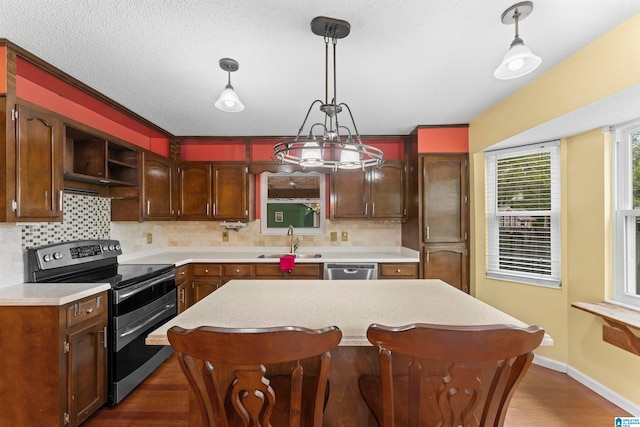 kitchen with pendant lighting, dark hardwood / wood-style flooring, stainless steel appliances, and sink