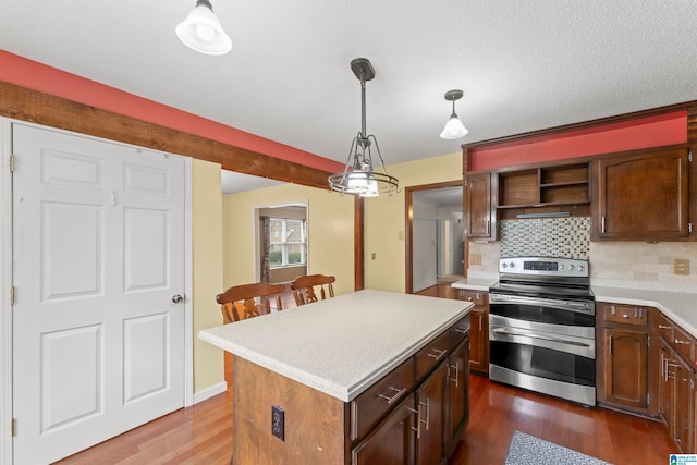 kitchen featuring decorative backsplash, dark wood-type flooring, decorative light fixtures, a center island, and stainless steel range with electric cooktop