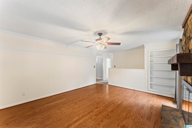 unfurnished living room with ornamental molding, hardwood / wood-style flooring, a fireplace, a textured ceiling, and ceiling fan