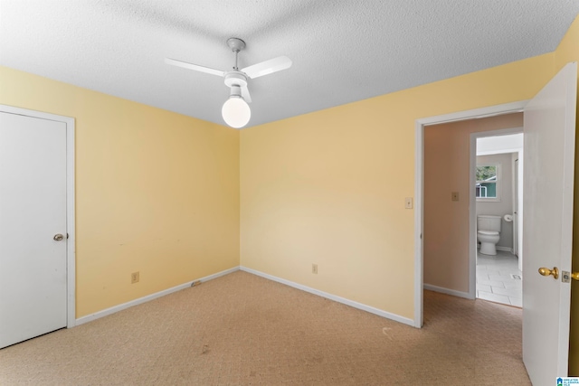 empty room featuring ceiling fan, light colored carpet, and a textured ceiling