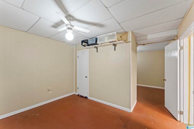 basement with a paneled ceiling and ceiling fan