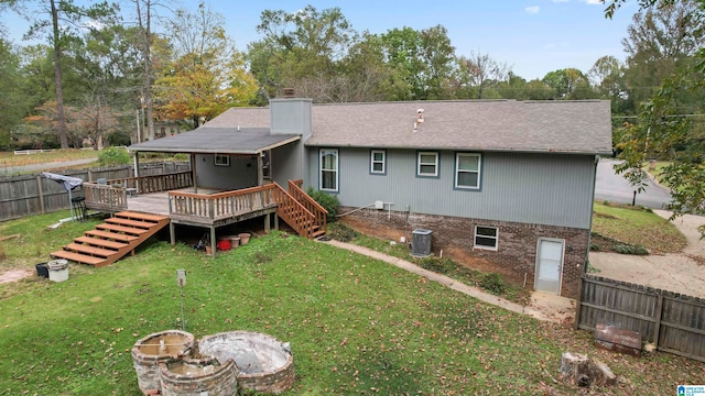 back of property with a lawn, a wooden deck, and central AC