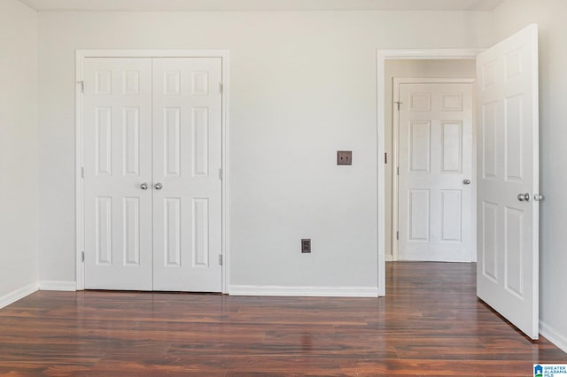 unfurnished bedroom with dark hardwood / wood-style flooring and a closet