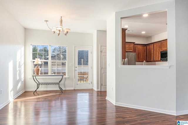 unfurnished dining area with dark hardwood / wood-style flooring and an inviting chandelier