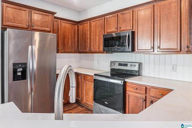 kitchen featuring light stone counters, dark wood-type flooring, and appliances with stainless steel finishes