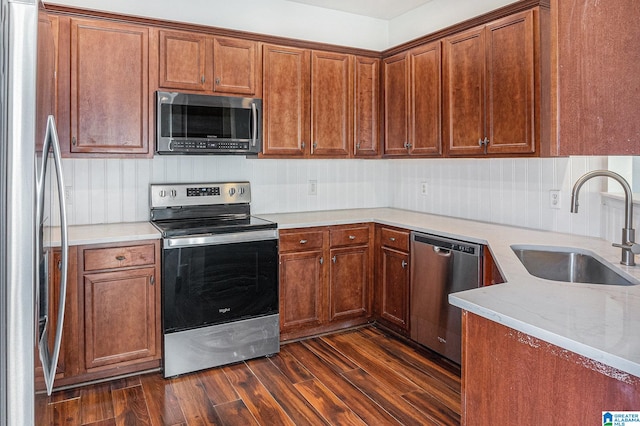 kitchen featuring dark hardwood / wood-style floors, light stone counters, sink, and appliances with stainless steel finishes