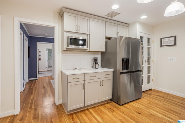 kitchen featuring crown molding, stainless steel appliances, backsplash, pendant lighting, and light hardwood / wood-style flooring