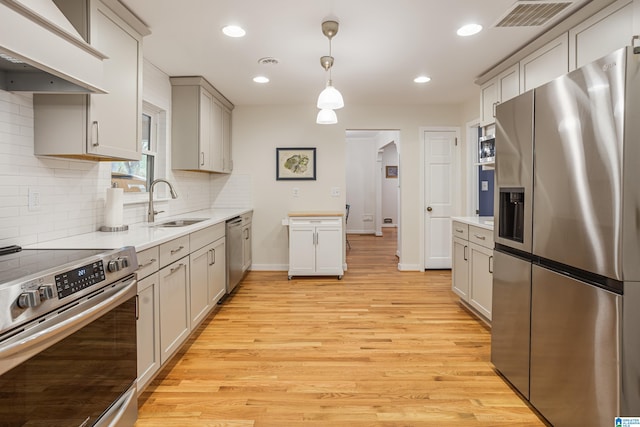 kitchen with light hardwood / wood-style floors, sink, gray cabinets, appliances with stainless steel finishes, and decorative light fixtures