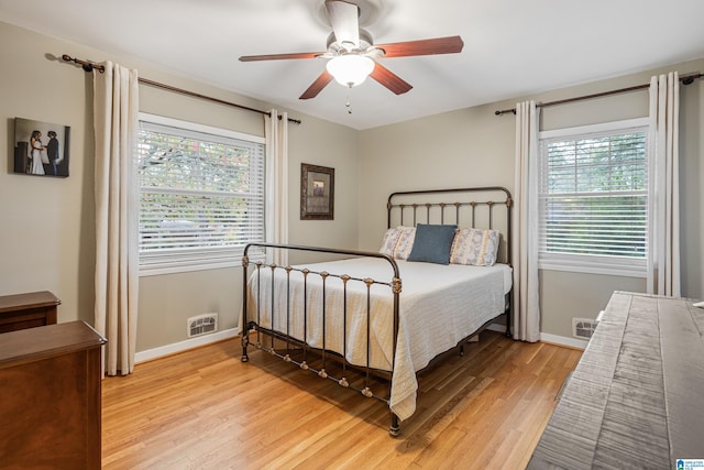 bedroom with light wood-type flooring, multiple windows, and ceiling fan