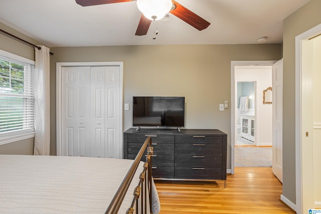 bedroom with light wood-type flooring, ceiling fan, and a closet