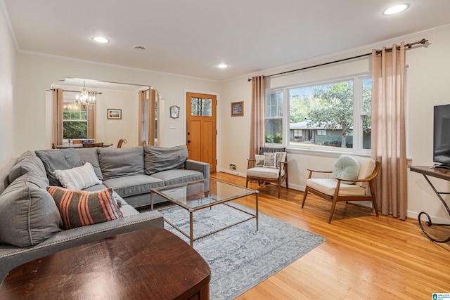 living room with a notable chandelier, light hardwood / wood-style floors, and crown molding