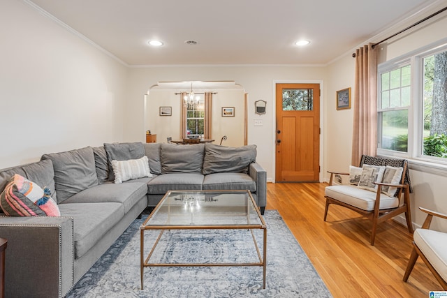 living room featuring light wood-type flooring, a chandelier, and ornamental molding