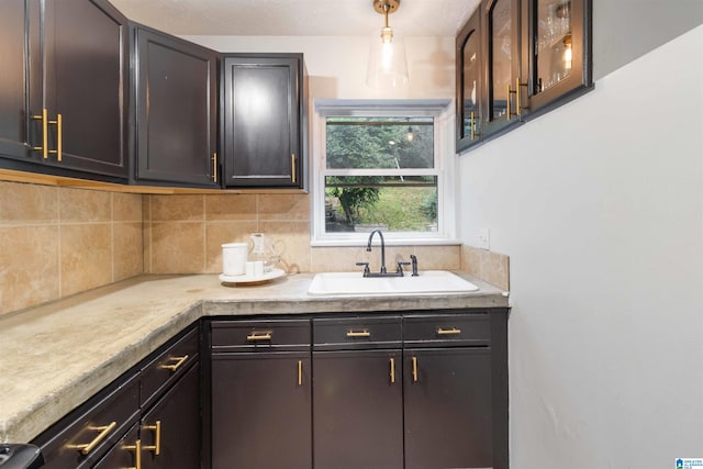 kitchen with pendant lighting, dark brown cabinets, decorative backsplash, and sink