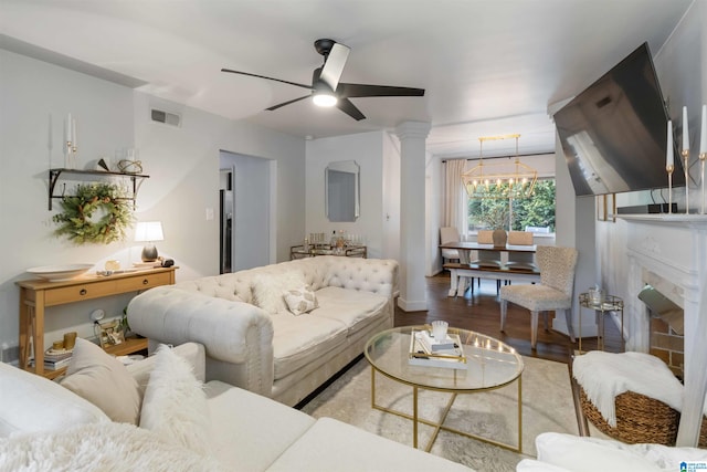 living room with wood-type flooring, ceiling fan with notable chandelier, and decorative columns