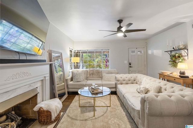 living room featuring a high end fireplace, wood-type flooring, and ceiling fan