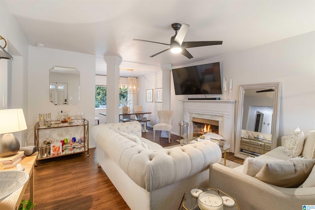 living room featuring ceiling fan with notable chandelier, a premium fireplace, and dark wood-type flooring