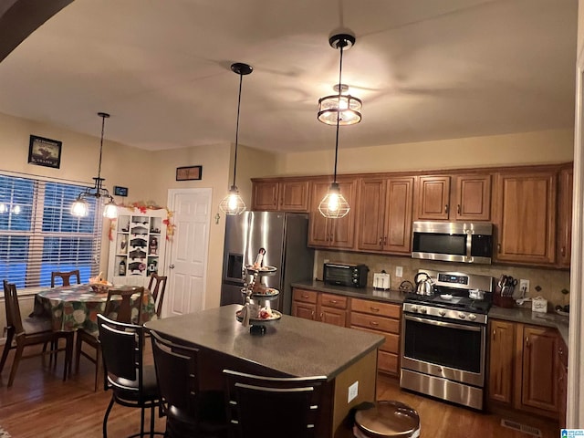 kitchen featuring pendant lighting, appliances with stainless steel finishes, dark hardwood / wood-style flooring, and tasteful backsplash