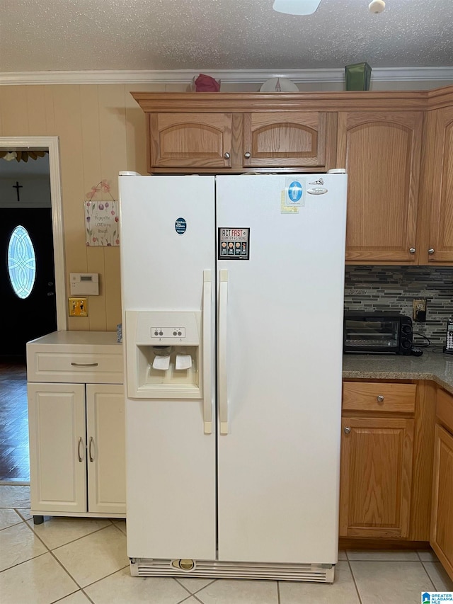 kitchen with decorative backsplash, a textured ceiling, light tile patterned floors, white fridge with ice dispenser, and crown molding