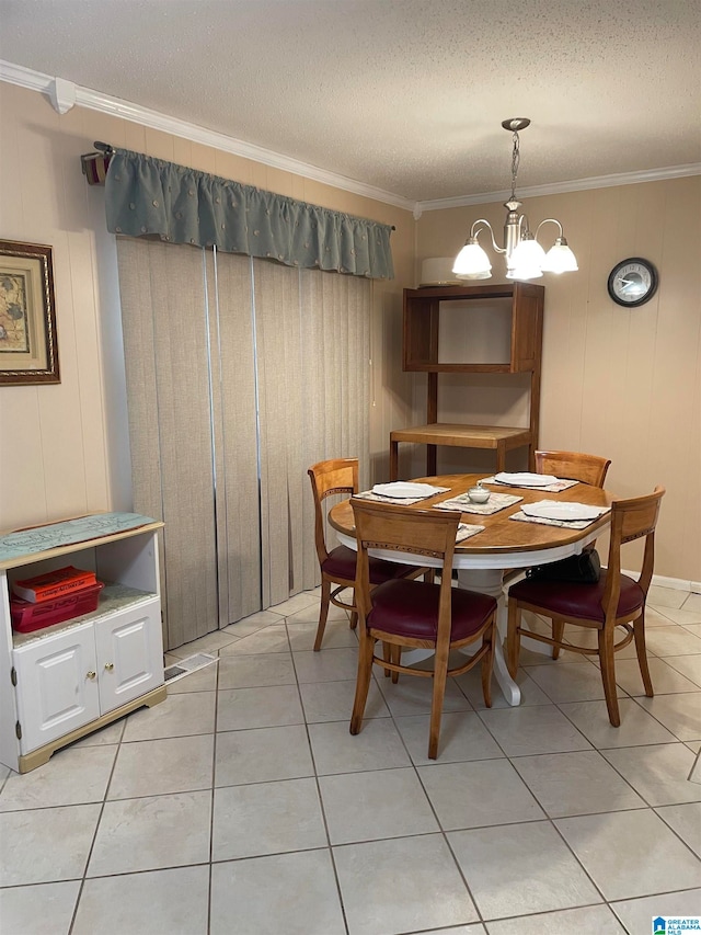 dining area featuring light tile patterned flooring, a textured ceiling, a notable chandelier, and ornamental molding