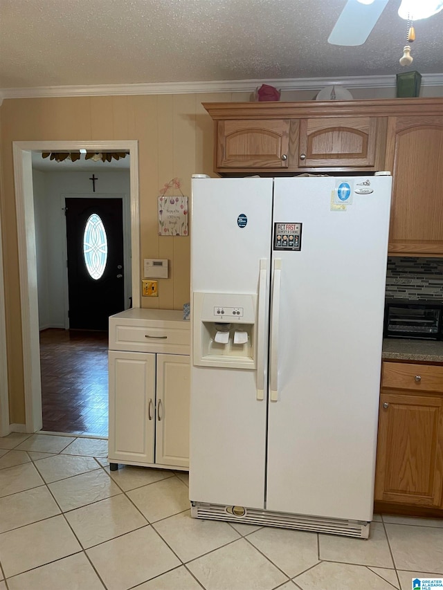 kitchen featuring a textured ceiling, ornamental molding, white fridge with ice dispenser, light tile patterned flooring, and backsplash