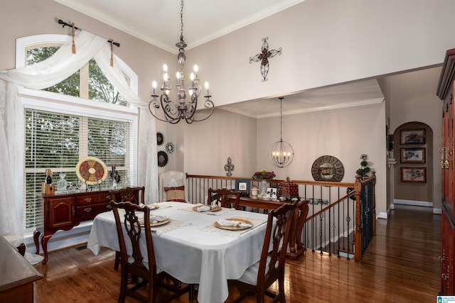 dining room featuring a towering ceiling, dark wood-type flooring, a chandelier, and crown molding