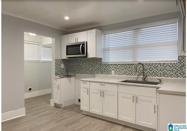 kitchen with white cabinetry, a wealth of natural light, sink, and light hardwood / wood-style floors