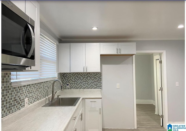 kitchen featuring decorative backsplash, white cabinetry, sink, and light wood-type flooring