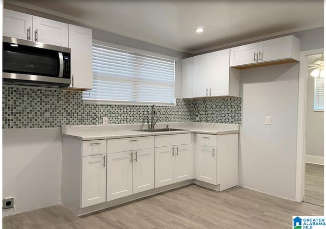 kitchen with white cabinets, sink, and light wood-type flooring