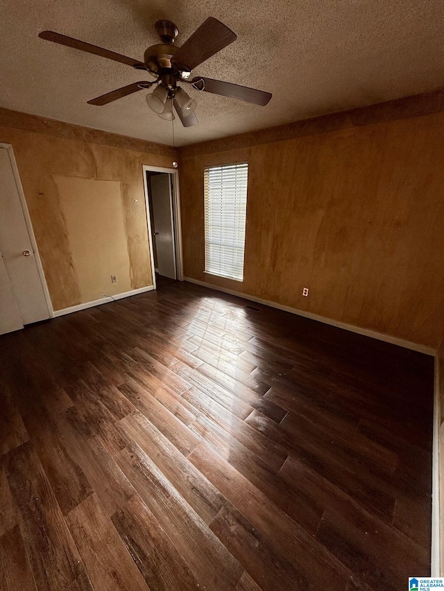 empty room featuring wood-type flooring, a textured ceiling, ceiling fan, and wooden walls