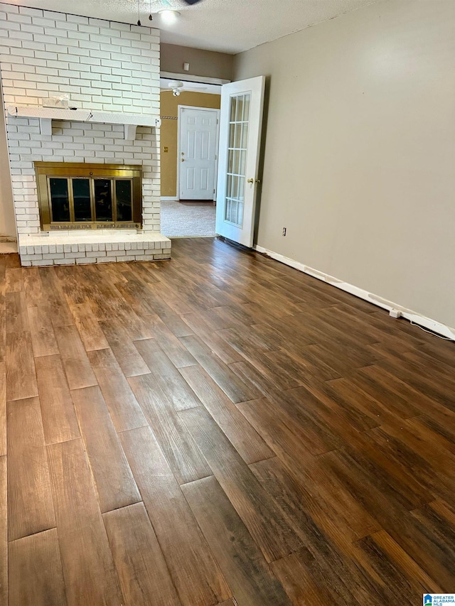 unfurnished living room with a fireplace, a textured ceiling, and hardwood / wood-style floors