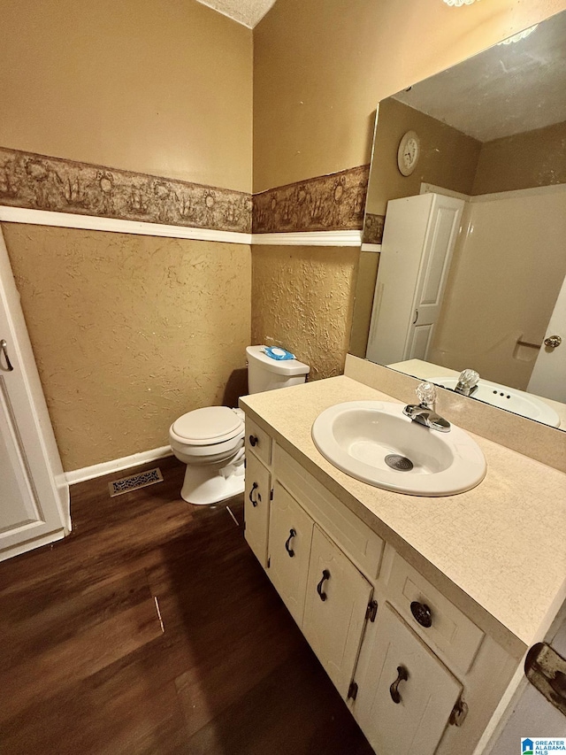 bathroom with hardwood / wood-style floors, walk in shower, vanity, and toilet