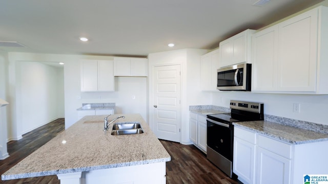 kitchen with appliances with stainless steel finishes, a center island with sink, sink, and dark hardwood / wood-style flooring