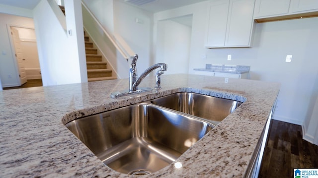 kitchen featuring dark hardwood / wood-style flooring, white cabinetry, light stone countertops, and sink