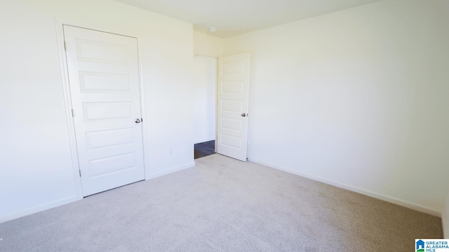 unfurnished bedroom with light colored carpet and a closet