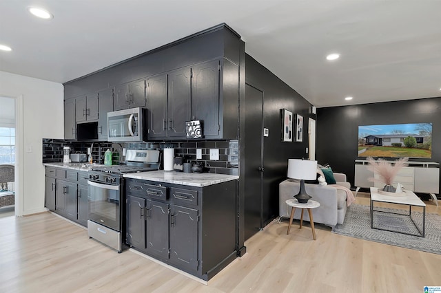 kitchen featuring tasteful backsplash, appliances with stainless steel finishes, light stone counters, and light hardwood / wood-style floors