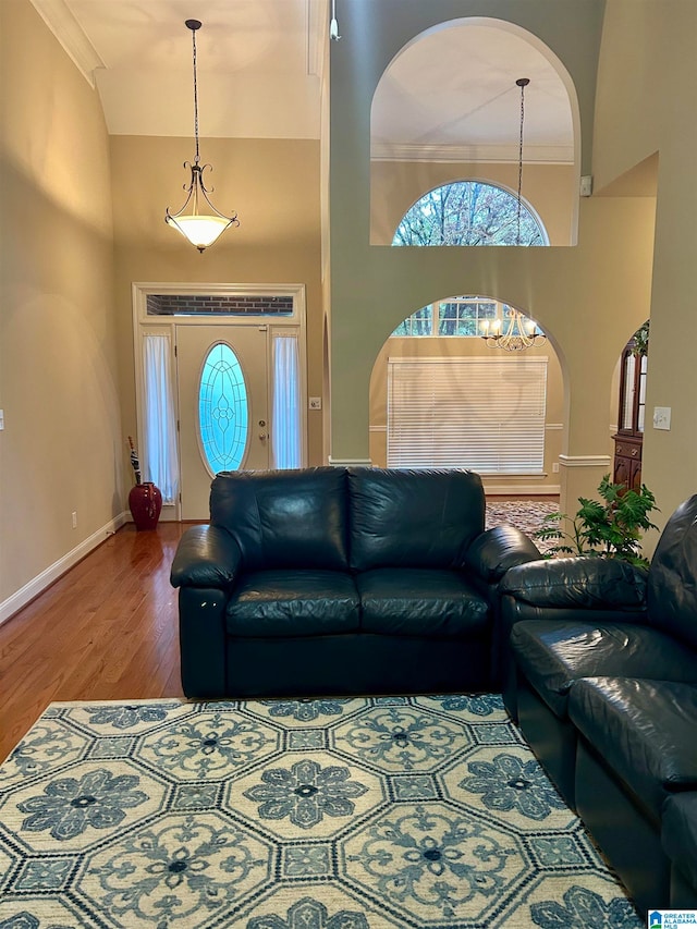 living room with hardwood / wood-style floors, crown molding, and a towering ceiling