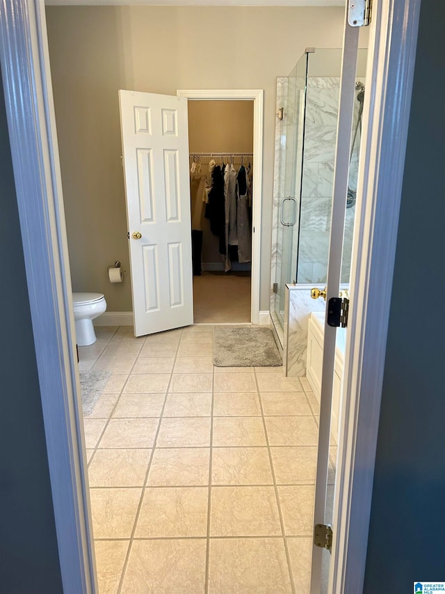 bathroom featuring toilet, an enclosed shower, and tile patterned floors