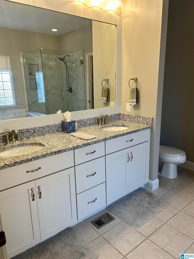 bathroom with toilet, vanity, tile patterned flooring, and a shower with door