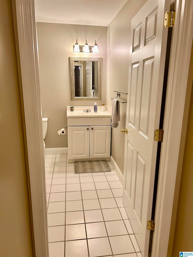 bathroom with toilet, vanity, and tile patterned flooring